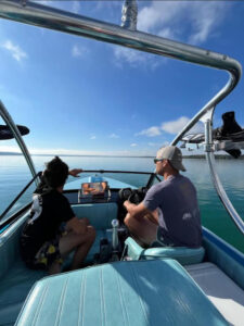 customer photo showing the customer driving their boat and showcasing their wake tower installed while sitting on the water. Boat has light blue interior.