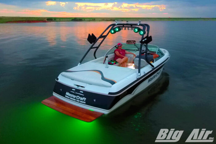 boat on water at sunset with green underwater lights and speakers
