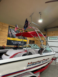 customer image shows a white and red mastercraft boat inside a garage. The boat has a red bimini cover. The back wall in the garage has a poster on the wall.