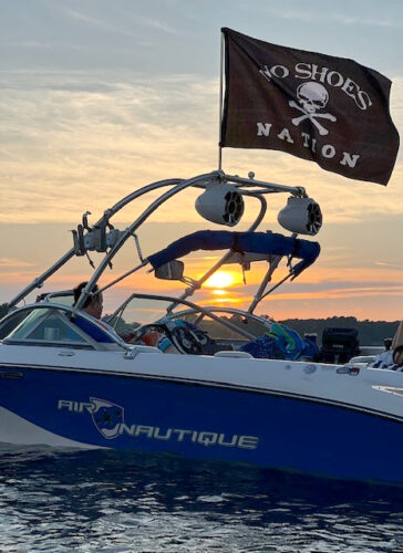 Nautique boat on the water at sunset with a pirate flag waving in the wind