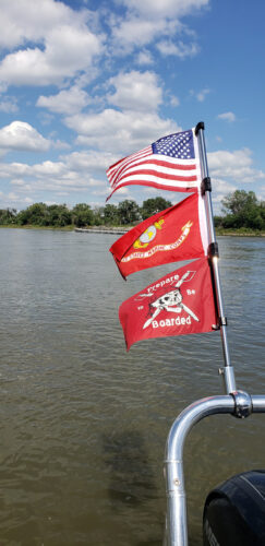 3 small flags waving on the back of a pontoon tower