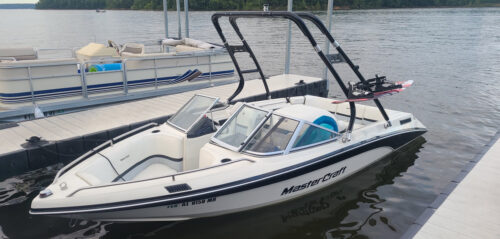 a boat sitting at the dock with a big air cuda wakeboard tower mounted ont ir