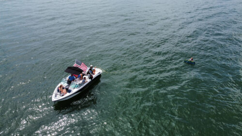 boat sitting in the middle of the water with a bimini top open and an american flag