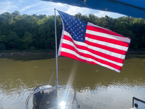 The American flag waving in the wind mounted onto a 46" pole via the Big Air Flag holder on a tritoon boat tower