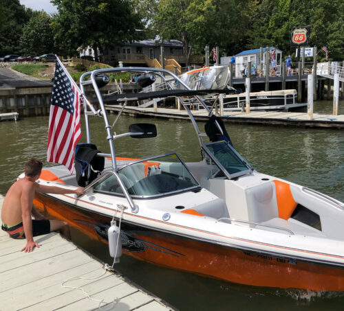 orange and white boat sitting at a dock with an american flag hanging off of the tower